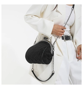 Close-up of black quilted shell bag with kiss-lock clasp worn with a white blazer