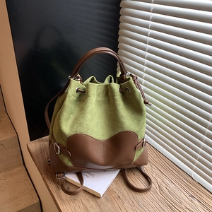Sac à dos vert avocat avec détails en cuir marron posé sur un escalier en bois