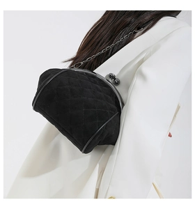 Detail of black quilted velvet shell bag with vintage metal clasp and chain strap
