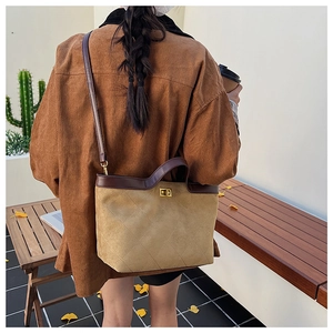 Detail of crossbody bucket bag with quilted stitching and gold buckle on a model