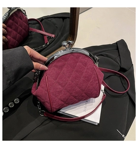 Close-up of quilted burgundy velvet shell bag with silver clasp and metallic chain strap