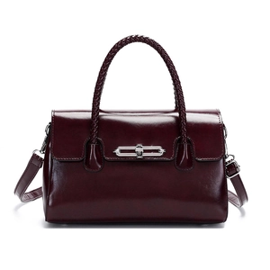 Detail of burgundy glossy leather handbag with woven handle and silver metal lock