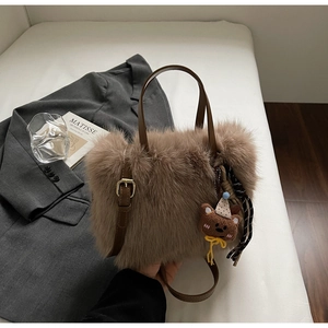Detailaufnahme der braunen Plüsch-Tasche mit Ledergriffen und niedlichem Bären-Anhänger