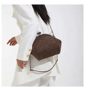 Detail of dark brown quilted suede shell bag with vintage metal clasp and chain strap