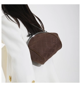 Brown suede doctor bag with quilted stitching and metal clasp shown on shoulder
