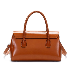 Detail of woven round handles and glossy leather texture on brown tote handbag