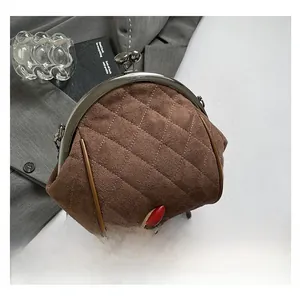 Detailed macro view of brown quilted suede shell bag with vintage metal kiss-lock closure