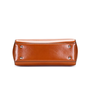 Detail of brown leather handbag base featuring protective silver metal feet and stitching