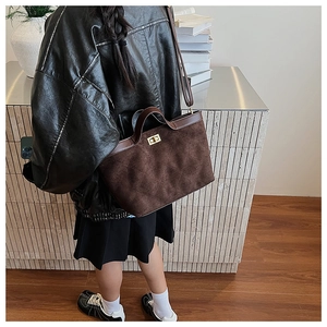 Detail of a brown quilted suede bucket bag with gold twist lock and sturdy top handle
