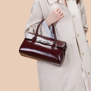 Elegant burgundy patent leather handbag with woven handle and gold metal clasp closure