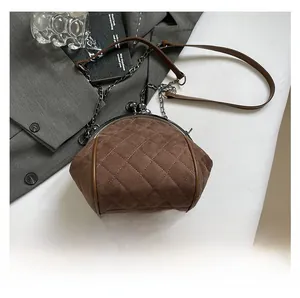 Detailed close-up of brown quilted crossbody bag with vintage clasp and metal chain