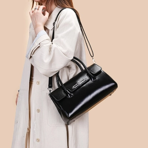 Detail of glossy black leather handbag with woven handle and silver metal bar closure