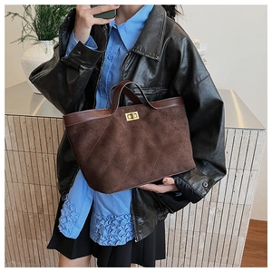 Detail of dark brown quilted suede bucket bag with gold clasp shown on a model
