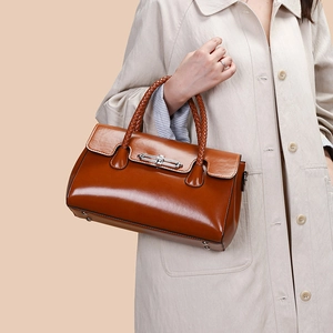 Detail view of woven leather handles and silver twist-lock on brown tote bag