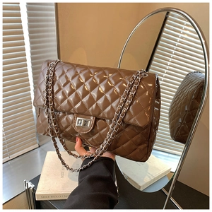 Detailed macro view of dark brown quilted shoulder bag with glossy finish and silver lock