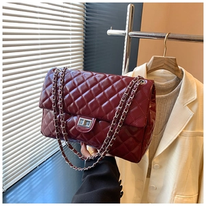 Detail of burgundy quilted leather bag with silver chain strap and metal turn-lock