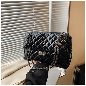 Detail of glossy quilted pattern and silver metal twist lock on the black chain bag