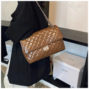 Detail shot of brown quilted crossbody bag with glossy finish and metal chain strap