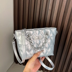 Detail of silver quilted crossbody bag featuring metal turn-lock and chain strap