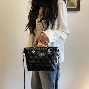 Detail of black quilted leather shoulder bag with silver clasp and chain strap