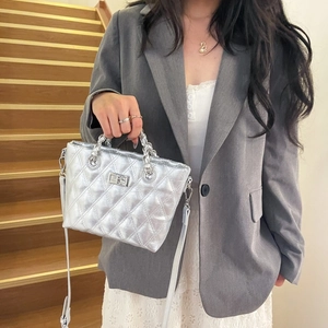 Detail of silver quilted crossbody bag with metal chain handle and twist lock closure