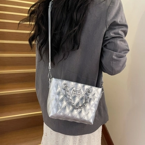 Close-up of silver quilted crossbody bag featuring metal turn-lock and chain handle