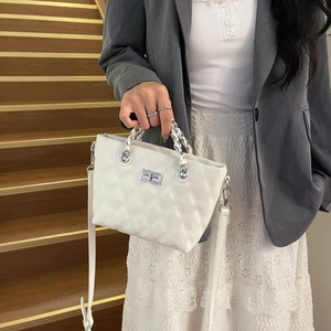 Close-up of white quilted crossbody bag with silver turn-lock and chain handle detail