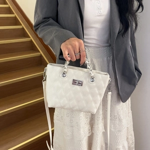 Close-up of white quilted crossbody bag with silver rotating lock and chain strap