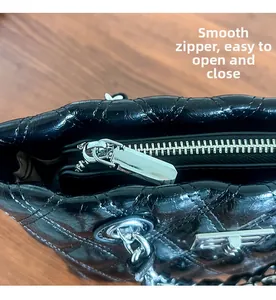 Detailed macro of the silver smooth zipper and quilted leather texture on crossbody bag