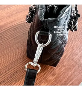 Detail of detachable silver hook and quilted chain strap on black crossbody bag