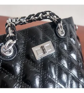 Detailed close-up of shiny black quilted leather texture and silver metal twist lock