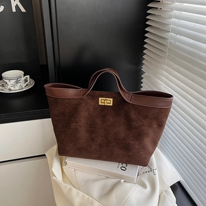 Brown suede bucket bag with quilted stitching and gold hardware in natural window light