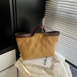 Brown quilted suede bucket bag with leather handles and golden twist lock on white cloth