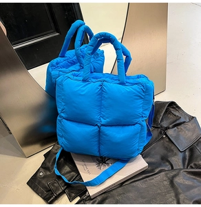 Détail d'un sac à main matelassé bleu électrique avec poignée rembourrée et texture nylon