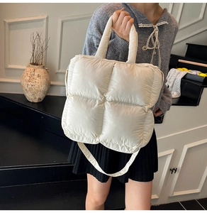 Gros plan sur le sac à main matelassé beige au fini nylon brillant et bandoulière souple