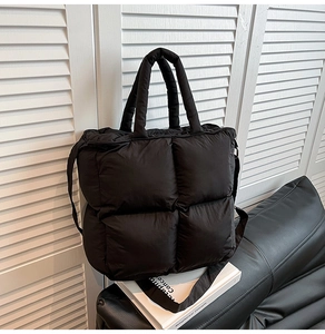 Détail du sac cabas matelassé noir avec poignées rembourrées sur une étagère blanche