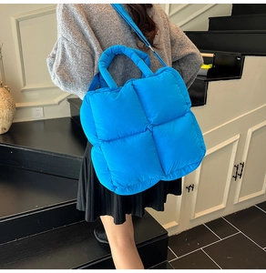 Sac à main bleu vif effet matelassé porté par un mannequin dans un escalier