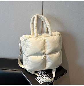 Détail d'un sac à main matelassé beige crème avec motifs carrés sur un livre noir