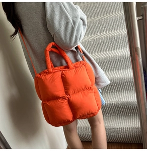 Sac fourre-tout matelassé orange vif porté à l'épaule avec des poignées rembourrées
