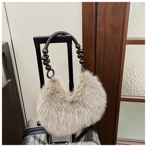 Detail of oat-beige plush fur handbag with dark brown wooden bead handle and metal rings