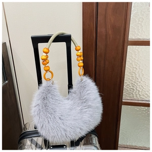 Detail view of grey faux fur handbag with bohemian wooden bead handle on suitcase