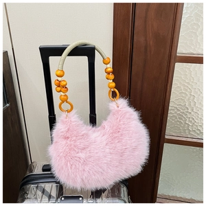 Detail of pink faux fur handbag with bohemian wooden bead handle on a suitcase