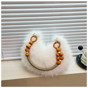 Detail of white faux fur handbag featuring unique beaded handle with gold metal rings