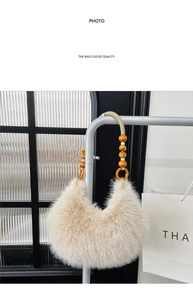 Detail of beige plush crescent bag featuring a woven handle with orange and white beads