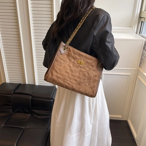 Borsa tote trapuntata marrone scuro con catena dorata indossata per mostrare lo stile