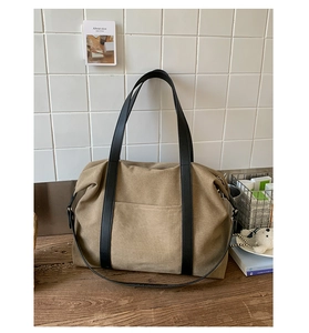 Détail macro du sac cabas en toile kaki avec anses en cuir noir et poche avant