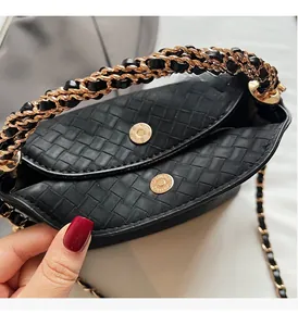 Detail of black woven texture handbag with golden chain and magnetic closures