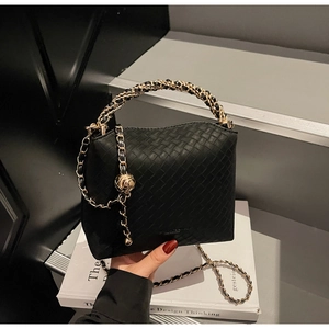 Detail of woven texture on black crossbody bag with gold chain and ball charm accessory