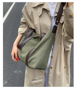 Détail d'un cabas en toile vert foncé avec anses cuir sur trench-coat beige