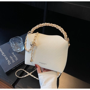 Detailed view of woven texture on white leather chain bag with golden hardware